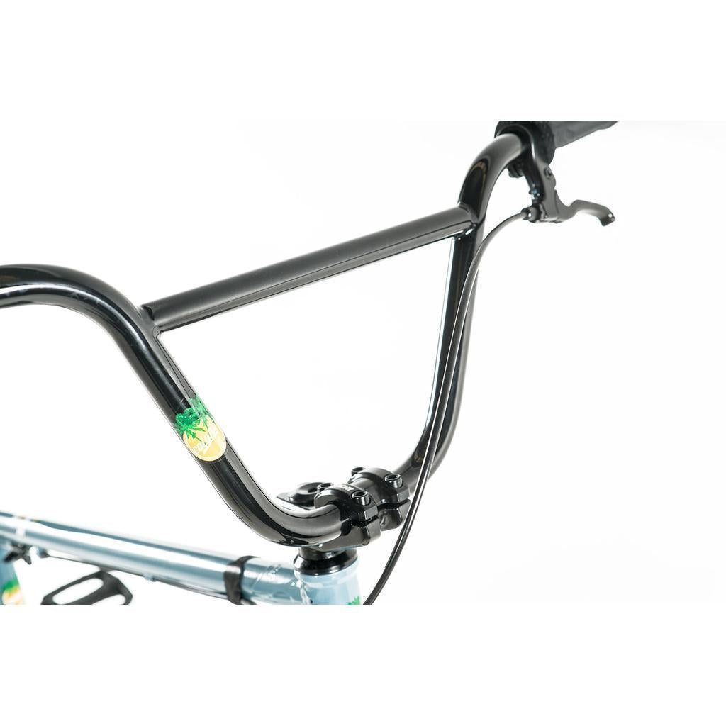 Close-up of a black BMX handlebar with brake lever mounted on the light blue chromoly frame of the Colony Eclipse 24 Inch Bike, set against a white background.