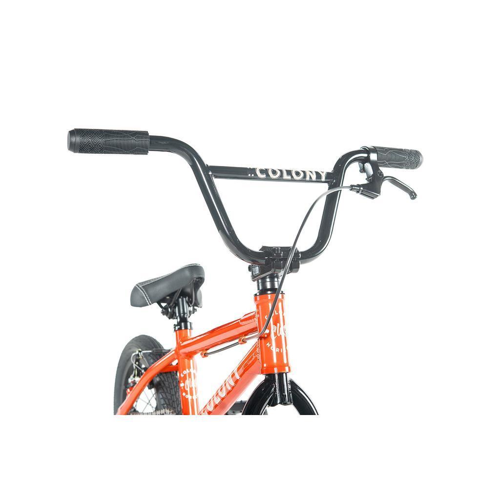 Close-up of the handlebars, seat, and frame of the Colony Horizon 14 Inch Bike in orange with a black "COLONY" handlebar against a white background—ideal for aspiring young freestyle riders.