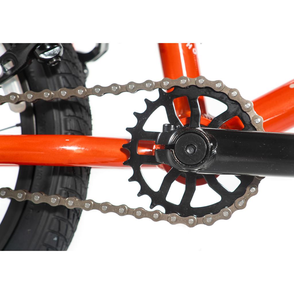 Close-up of a black pedal crank, chainring, and chain on an orange frame with black tire—perfect details found on the Colony Horizon 16 Inch Bike, designed for freestyle BMX riding.