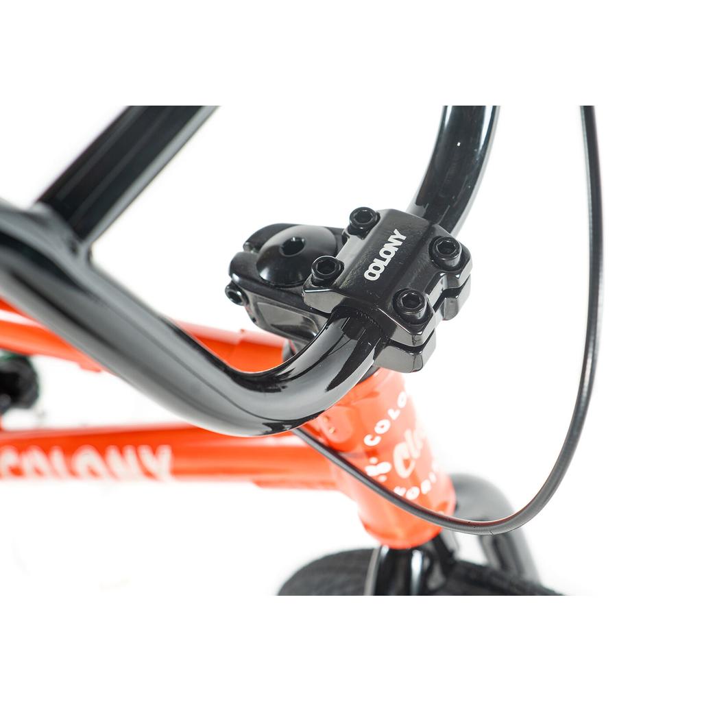 Close-up of a black handlebar and stem on an orange Colony Horizon 16 Inch Bike, a leading freestyle BMX, against a white background.
