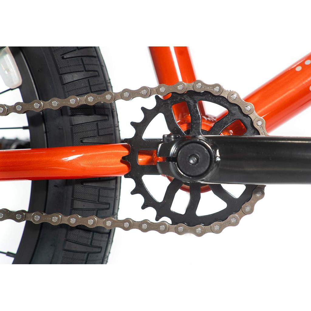 Close-up of the Colony Horizon 20 Inch Bike’s rear wheel, featuring the chain, orange frame, black crank arm, and gear sprocket against a white background.