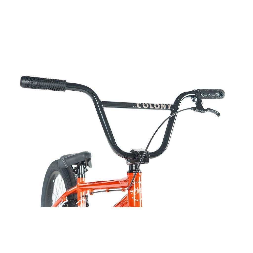 Close-up of the Colony Horizon 20 Inch Bike’s handlebars and brake lever, featuring the "Colony" brand on the crossbar. The orange frame highlights its BMX Freestyle style.
