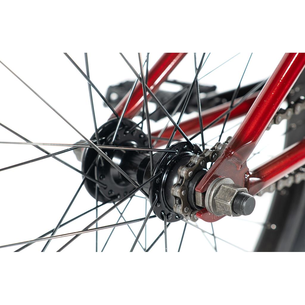 Close-up of the rear wheel hub, sprocket, and spokes on a red colony-emerge-bike-2020, highlighting the axle bolt and part of the bike frame against a white background.
