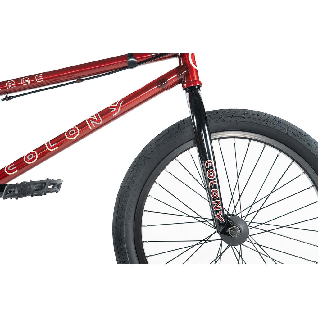 Close-up of the colony-emerge-bike-2020, a red and black BMX featuring its frame, front fork, and front wheel with thick treaded tire and spokes.