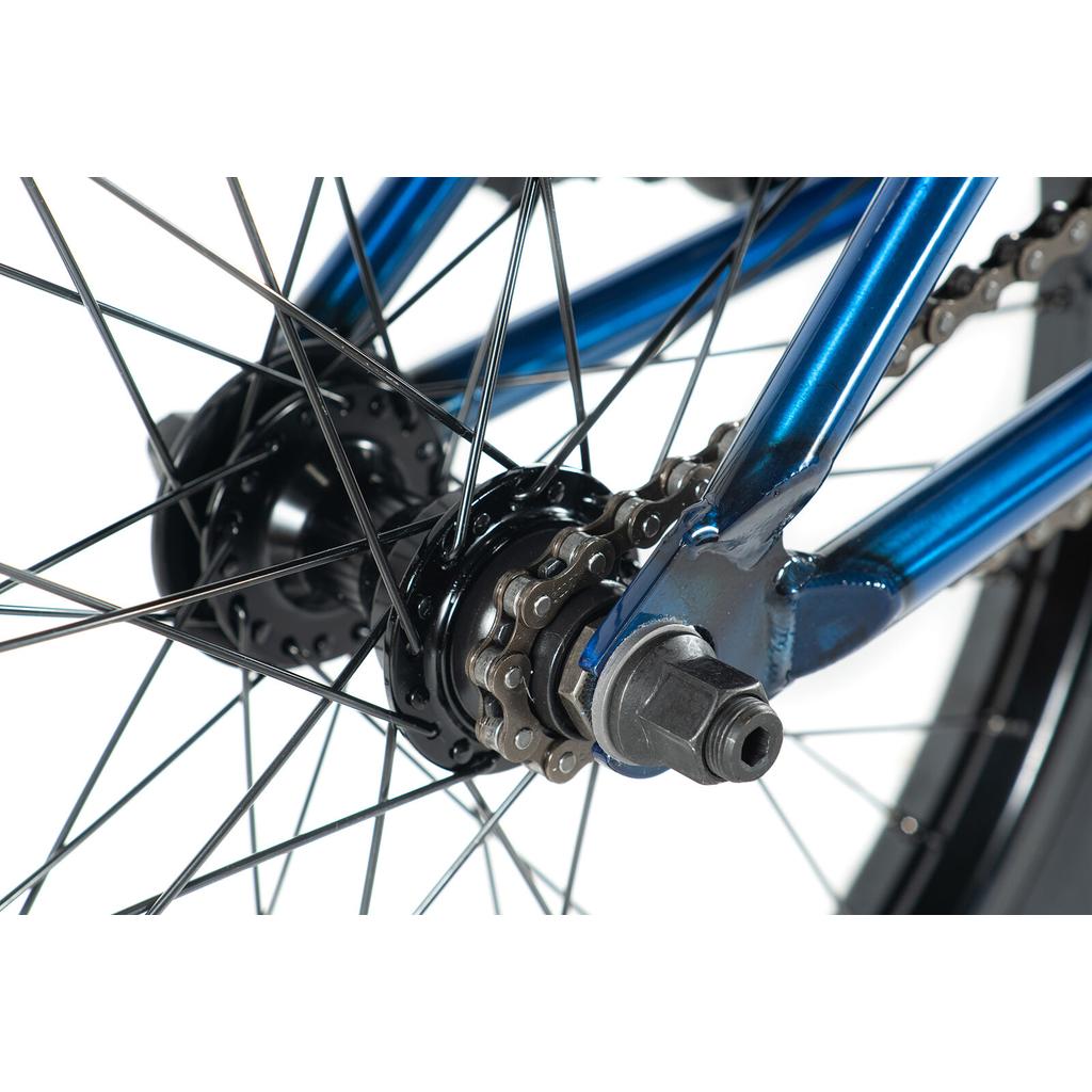Close-up of the Colony Premise 20 Inch Bike’s rear wheel, showcasing its sealed cassette hub, metal spokes, chain, and part of the robust blue chromoly frame.
