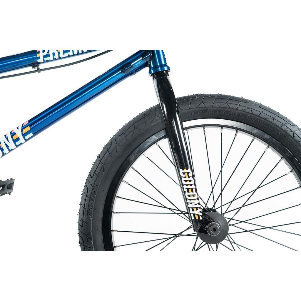 Close-up of the front wheel and fork of a Colony Premise 20 Inch Bike with black tire, double-wall rims, black spokes, and blue frame on a white background.