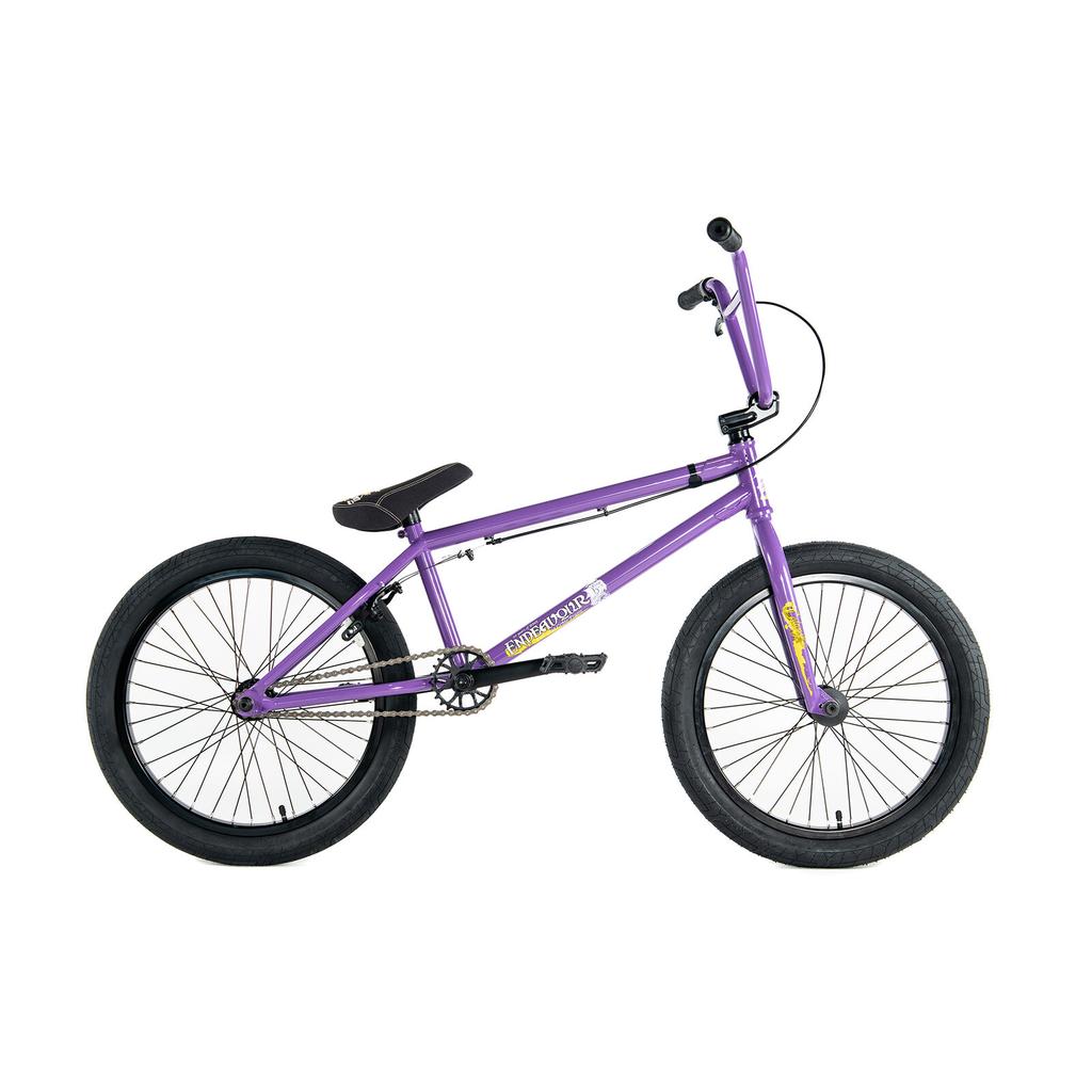 A side-profile of the purple Colony Endeavour Bike BMX features a tough Chromoly frame, black tires, padded seat, and wheel pegs, displayed against a white background.