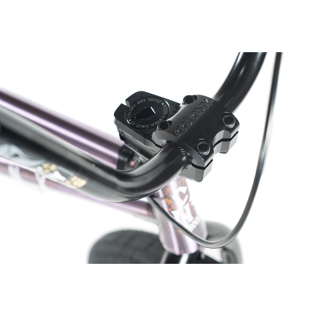 Close-up of a black stem and handlebars on the Colony Rico Elite 20 Inch Bike's purple frame, with part of the front wheel visible, showcasing pro-level performance.