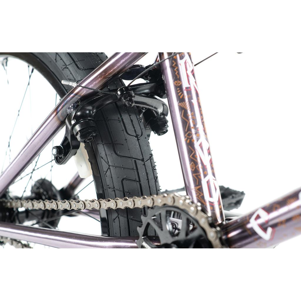 Close-up of the Colony Rico Elite 20 Inch Bike’s rear wheel, highlighting the tire, chain, cassette, and part of the frame with geometric graphics for pro-level BMX performance.