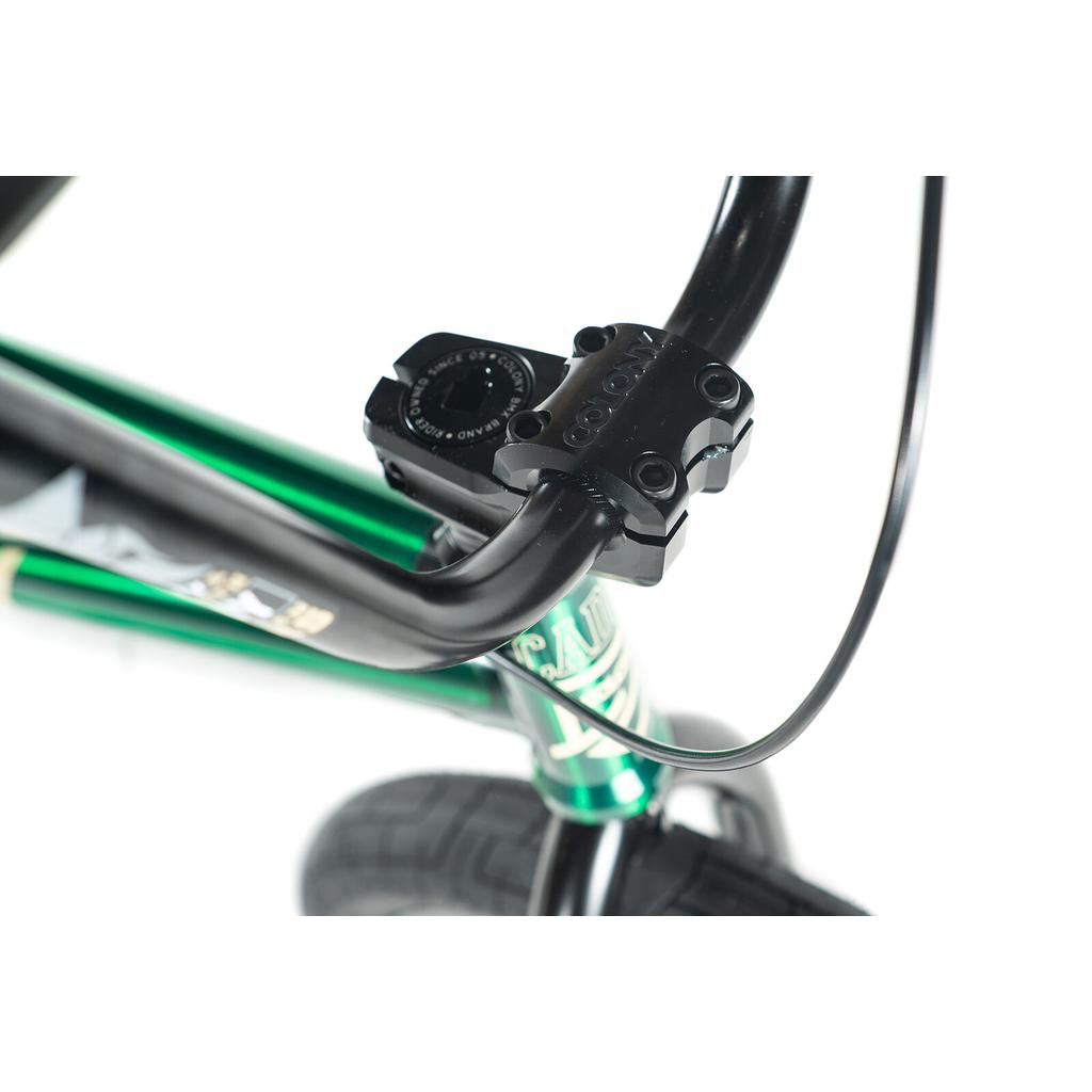Close-up of the Colony Cadet Elite 20 Inch Bike’s black handlebar and stem on a green full CrMo frame, front wheel and brake cable visible, highlighting the stable geometry built for pro-level BMX performance.