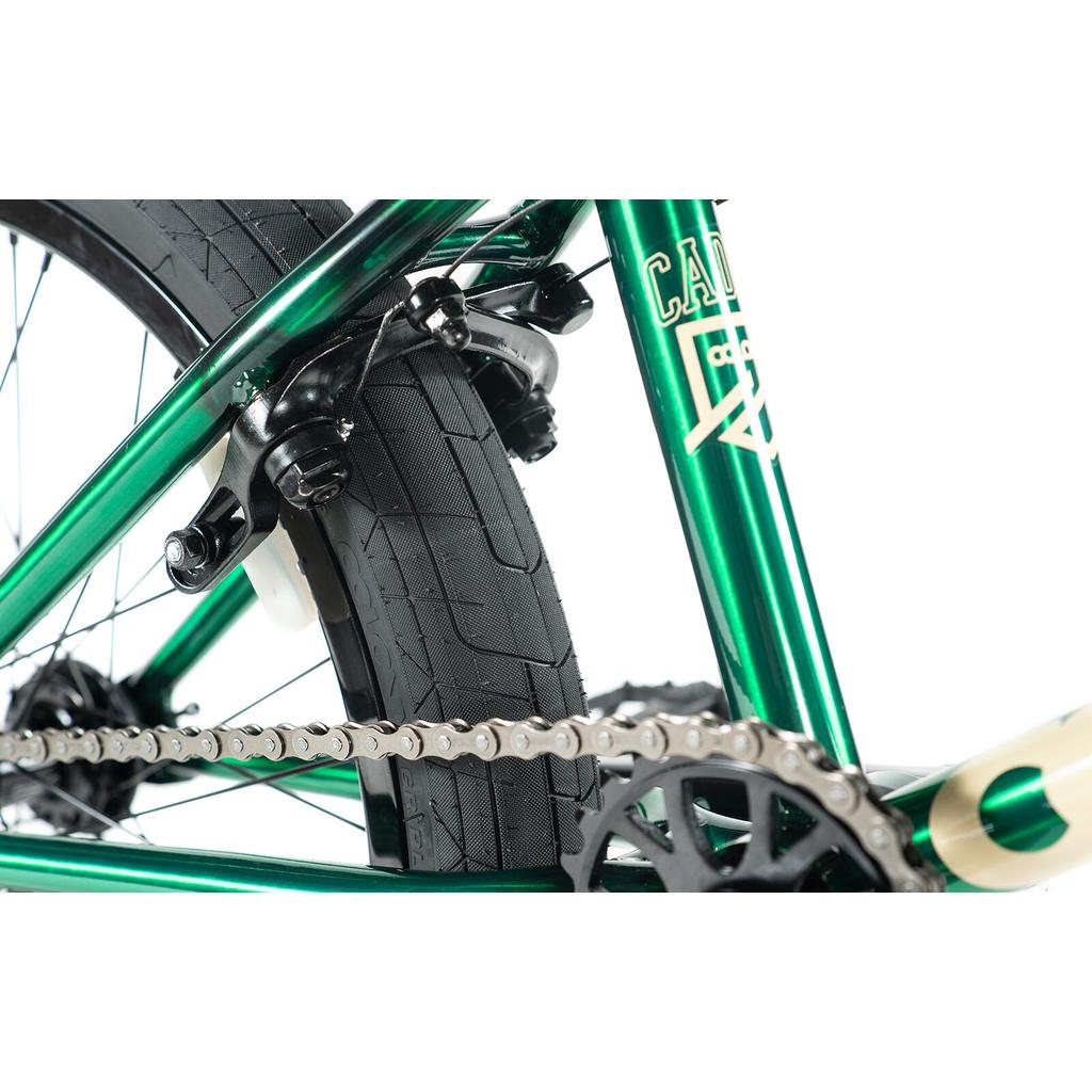 Close-up of a green Colony Cadet Elite 20 Inch Bike’s rear wheel, highlighting the tire, chain, sprocket, and brake assembly against a white background.