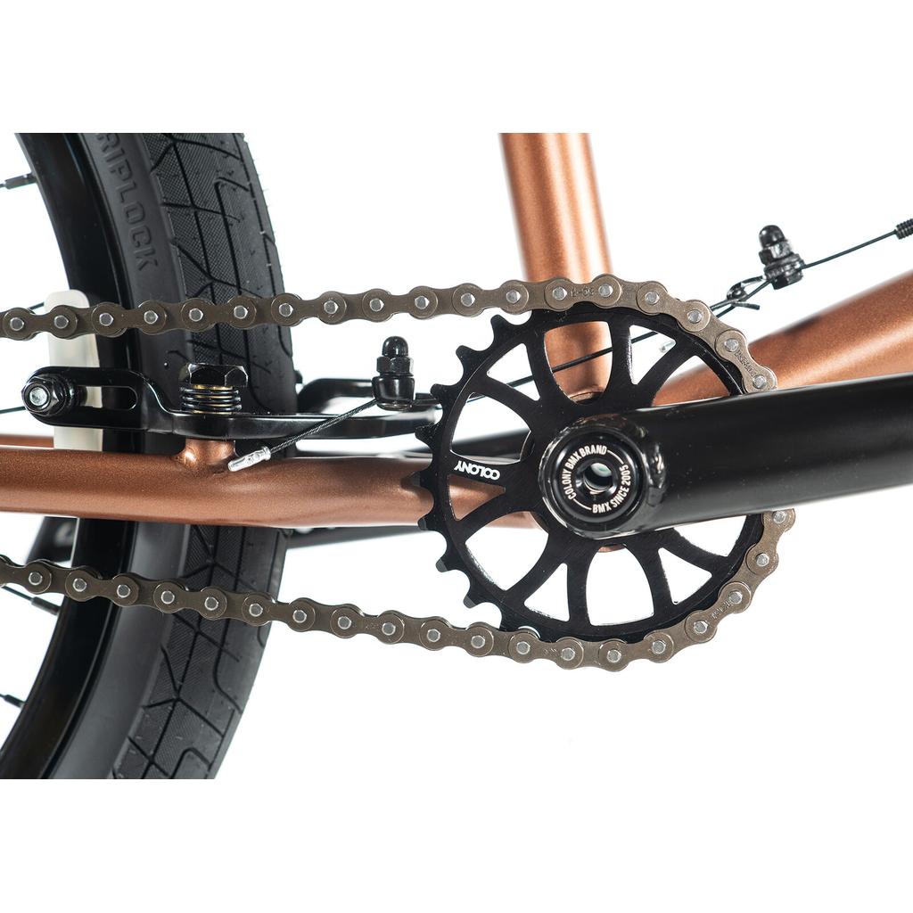 Close-up of the Colony Prody Elite 20 Inch Bike's BMX drivetrain, highlighting the chain, rear wheel, pedal crank, and chainring on its durable CrMo frame against a white background.