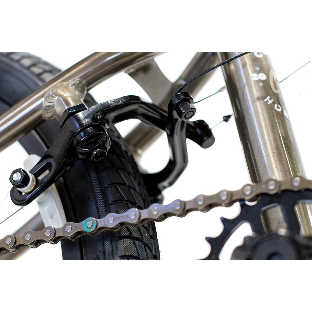 Close-up of the Colony Horizon 18 Inch Bike’s rear wheel, showcasing the brake caliper, tire tread, lightweight alloy frame, chain, and part of the gear assembly in detail.