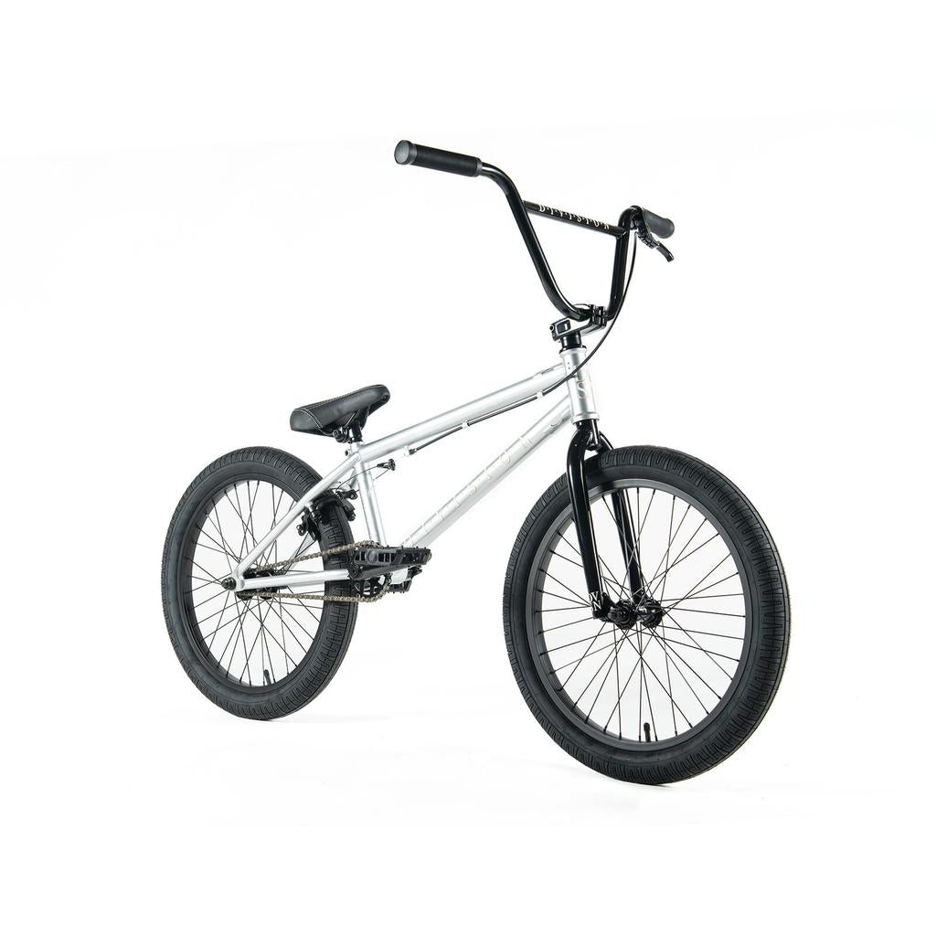 The Division Reark 20 Inch Bike in silver and black features thick tires, a padded seat, upright handlebars, and 3-piece cranks, shown on a white background.