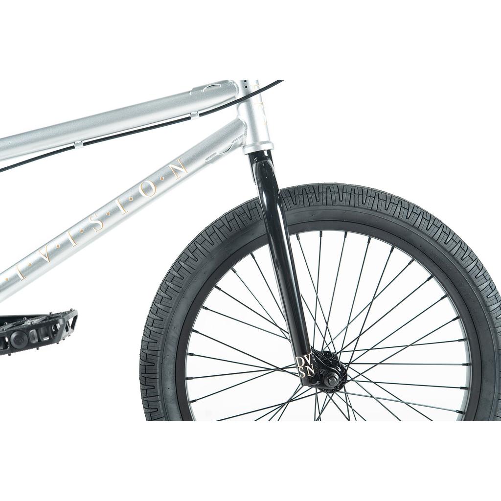 Close-up of the front wheel and fork of the Division Reark 20 Inch Bike in silver with black tires, showcasing Hi-Tensile steel construction, set against a white background.