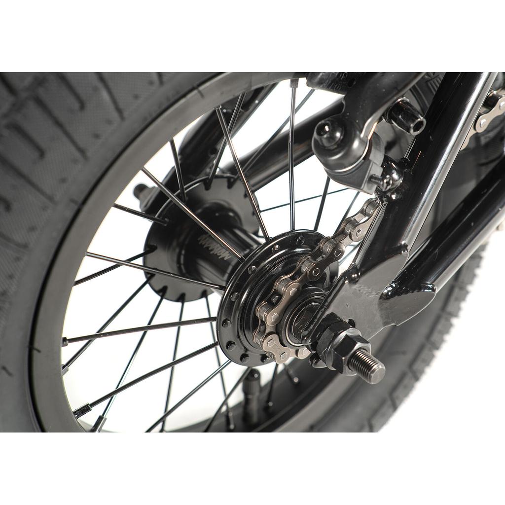 Close-up of the Division Blitzer 12 Inch Bike's rear wheel, displaying the tire, spokes, gear cog, chain, and axle against a white background.