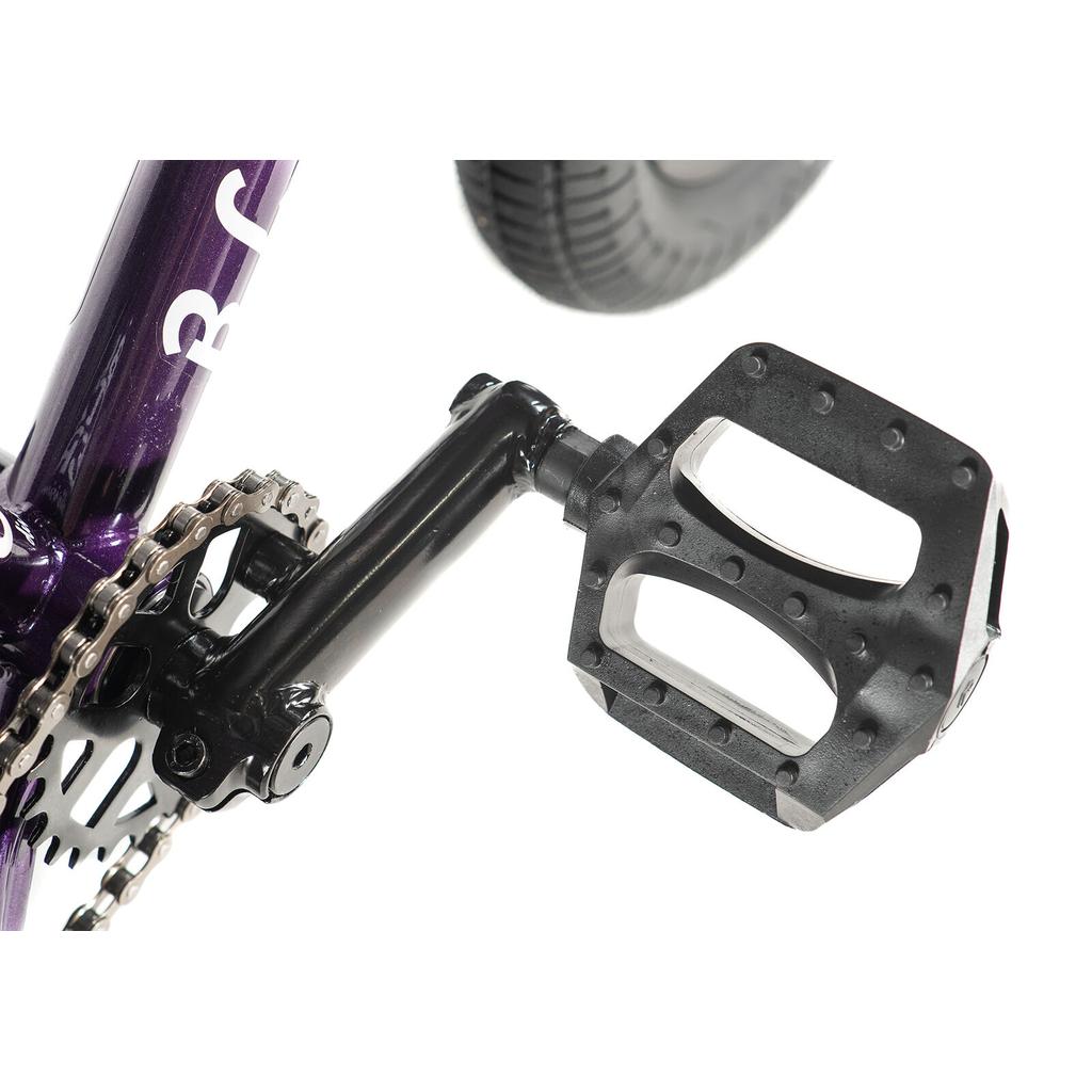 Close-up of a black pedal attached to the crank arm, with part of the chainring, chain, and a wheel visible—ideal for the Division Blitzer 12 Inch Bike.