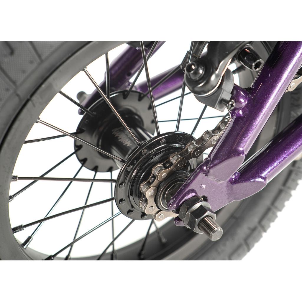 Close-up of the Division Blitzer 12 Inch Bike's rear wheel, showing the black hub, gear cog, spokes, and a section of its purple freestyle BMX frame.