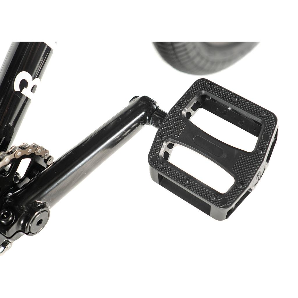 Close-up of a black pedal attached to the crank arm on the Division Blitzer 18 Inch Bike, showing part of the Hi-Ten frame, chain, and tire in the background.