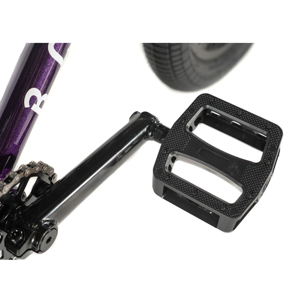 Close-up of a black pedal and crank arm on the Division Blitzer 18 Inch Bike, with parts of the Hi-Ten frame and rear tire visible in the background.