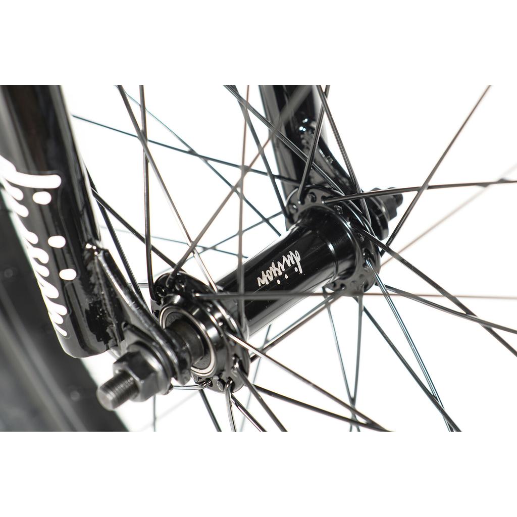 Close-up of a black front wheel hub with spokes and axle nuts, featuring "Mission" on the hub—ideal for beginners starting out on the Division Blitzer 20 Inch Bike.