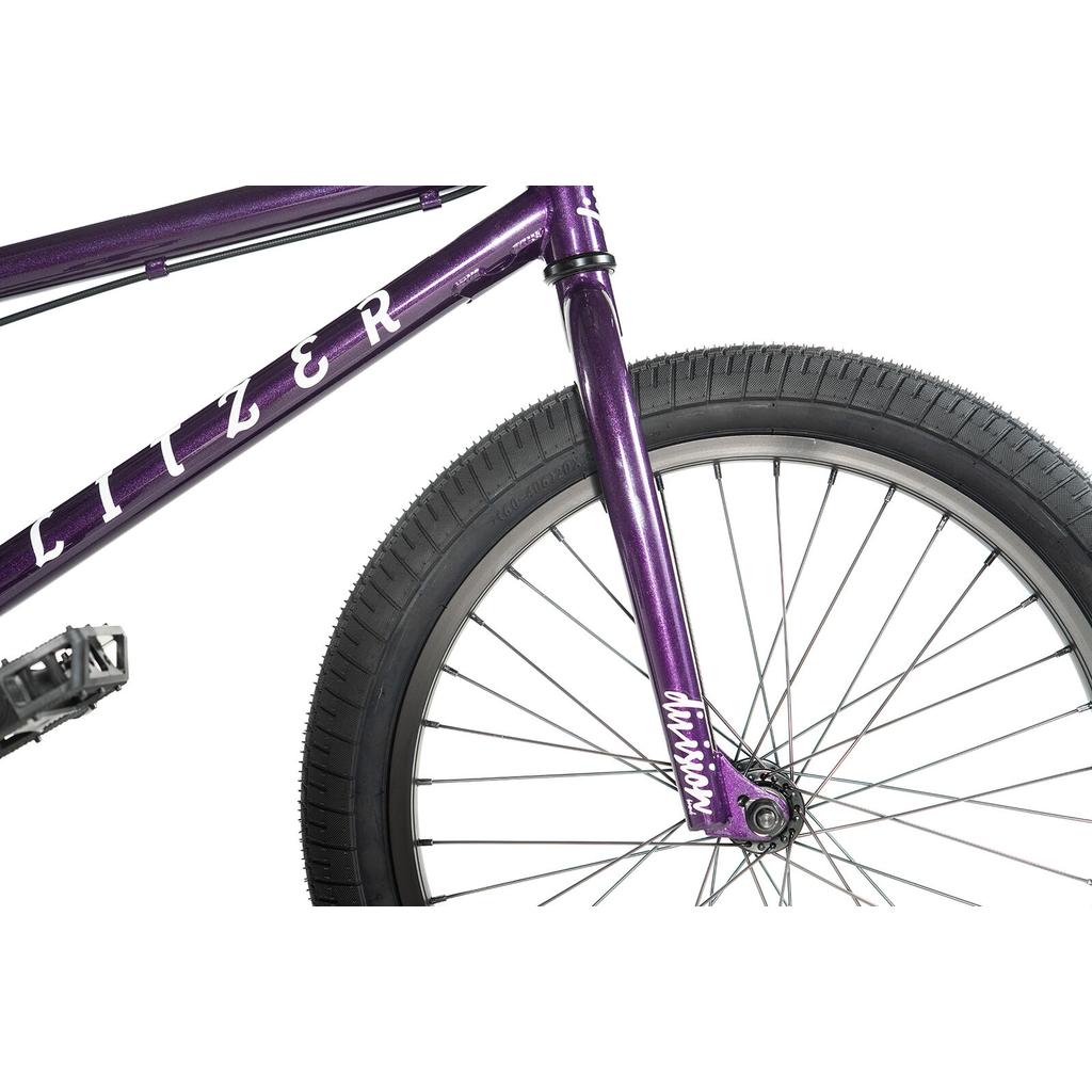 Close-up of the Division Blitzer 20 Inch Bike’s purple front wheel and fork, featuring silver spokes, a black tire, and "DIVISION" on the fork. Perfect for beginner street BMX riders with durable 20” wheels.