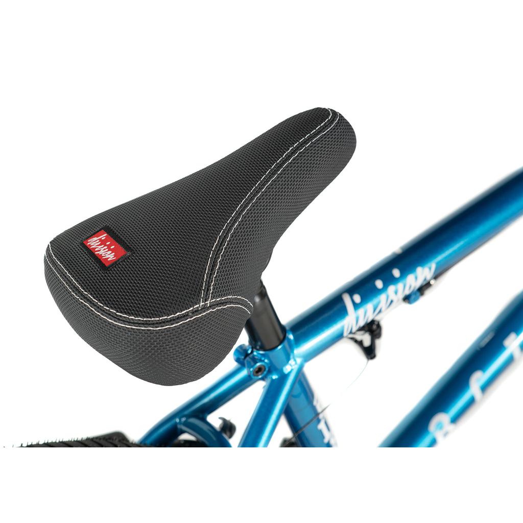 Close-up of a black textured seat with white stitching on the Division Blitzer 20 Inch Bike, a metallic blue beginner BMX featuring 20” wheels.
