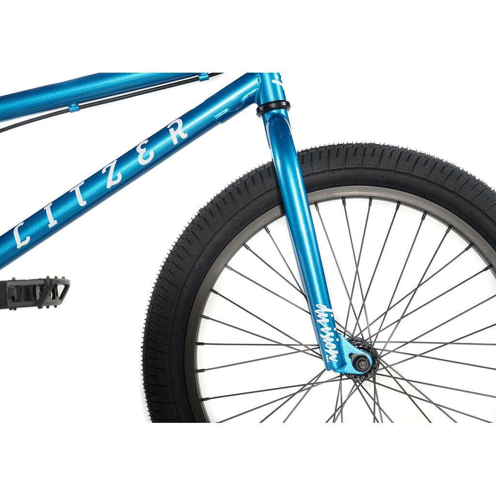 Close-up of the Division Blitzer 20 Inch Bike’s front section, featuring blue frame, 20” wheels, tire, fork, and visible "LITZER" branding.