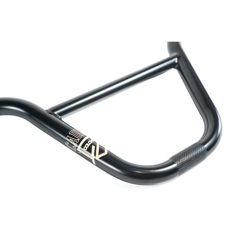 Close-up of a black Colony Cadet Bars handlebar featuring the logo and a textured grip area on one side, photographed against a white background.