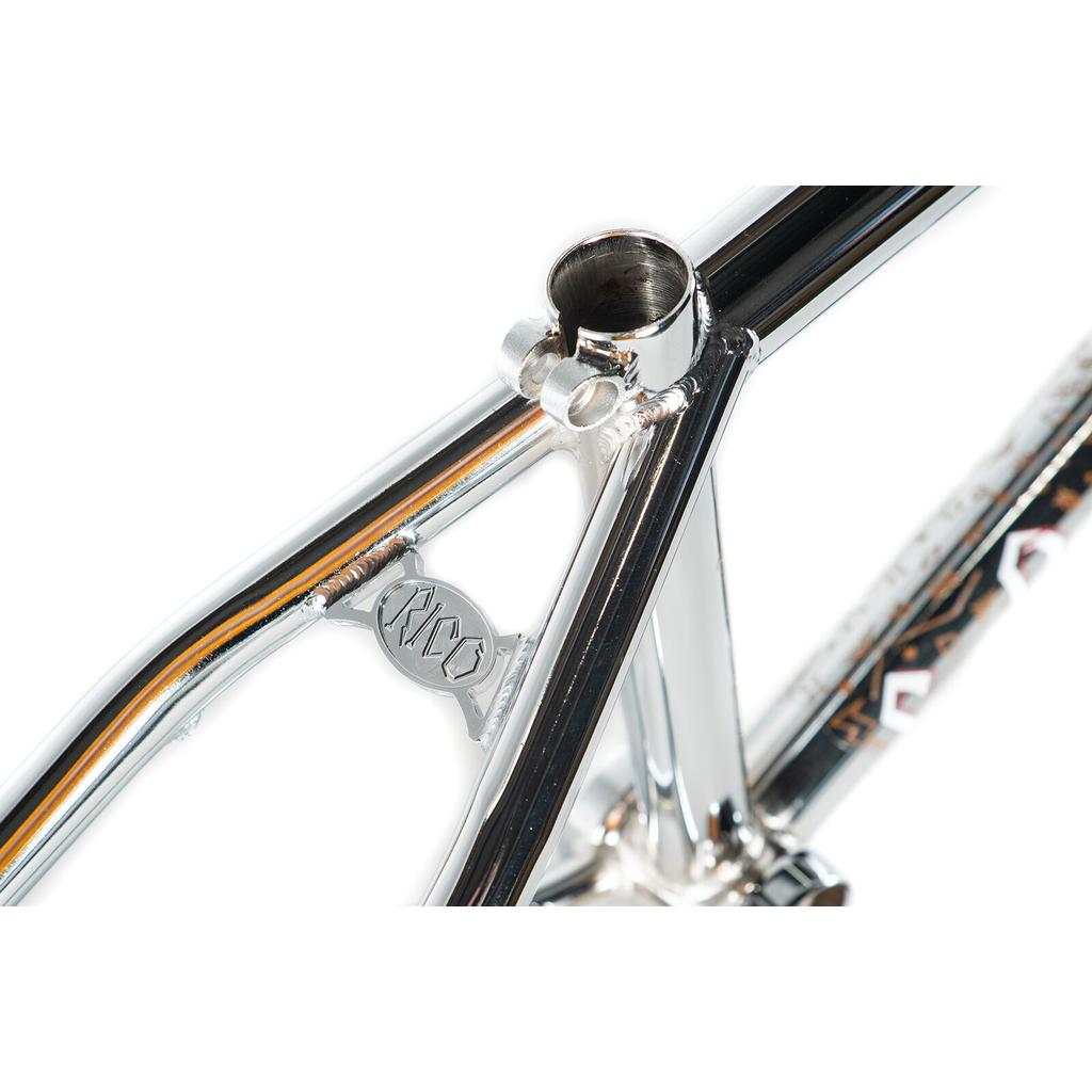 Close-up of the Colony Rico 'Lite' Frame—chrome, full CrMo construction—showing welded seat tube junction and a small metallic "RWC" badge on the rear triangle, ideal for technical park and ramp riding.