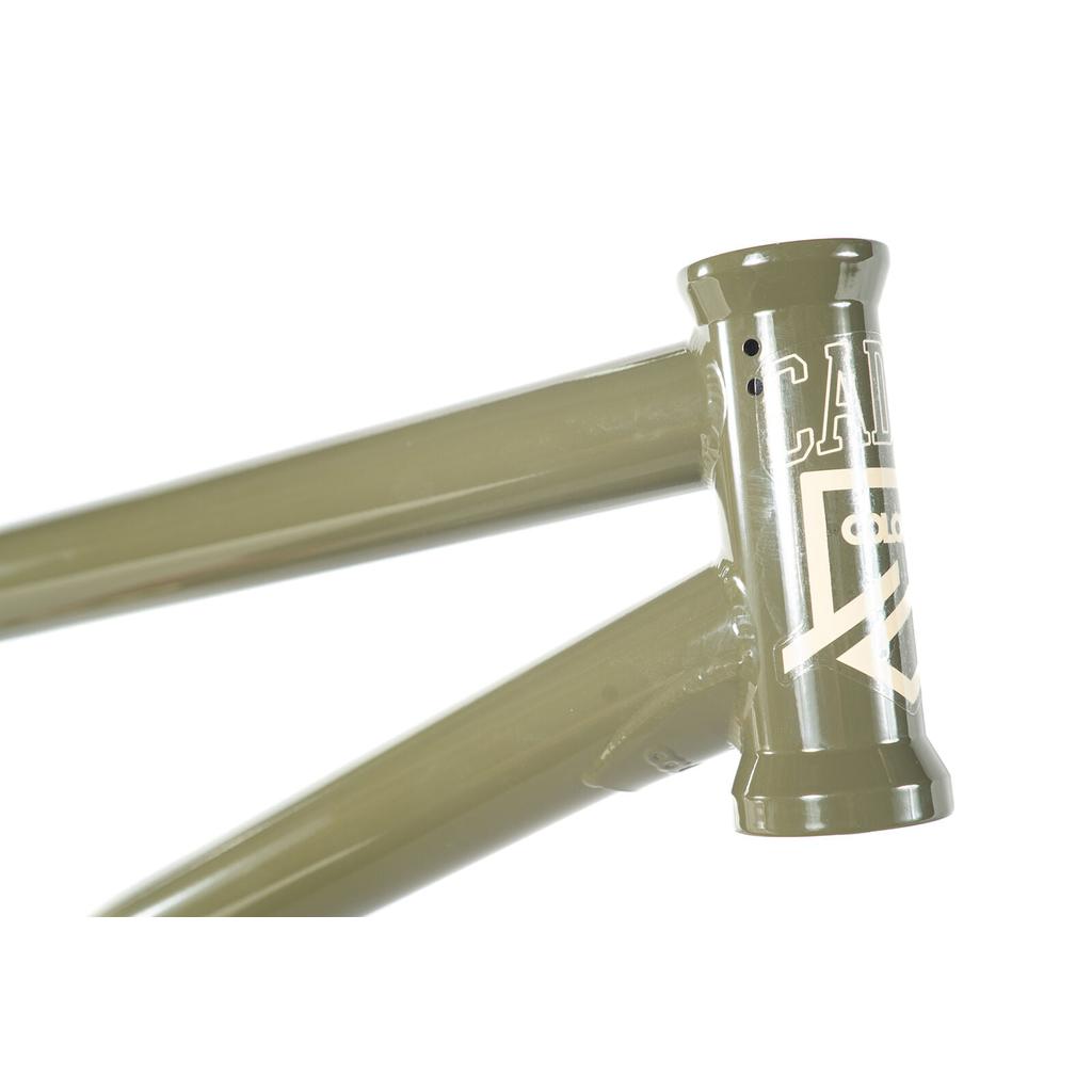 Close-up of the Colony Cadet 20 inch Frame in olive green, showcasing a white graphic and logo on the head tube. Built with durable chromoly for park and street BMX geometry.