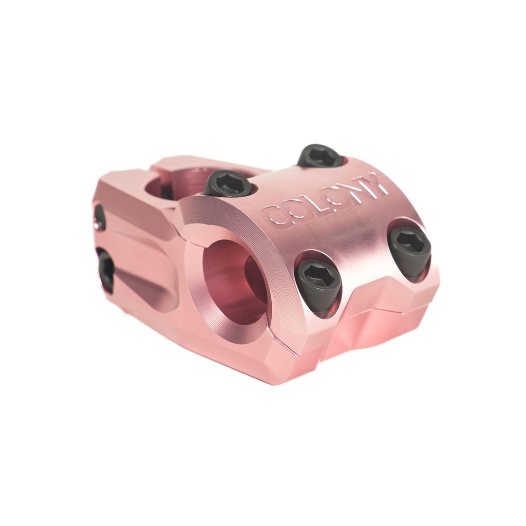 The Colony Variant 35mm Stem is a pink metal low-rise BMX stem with black bolts and an embossed "Colony" logo on the front, designed to elevate your BMX riding experience.