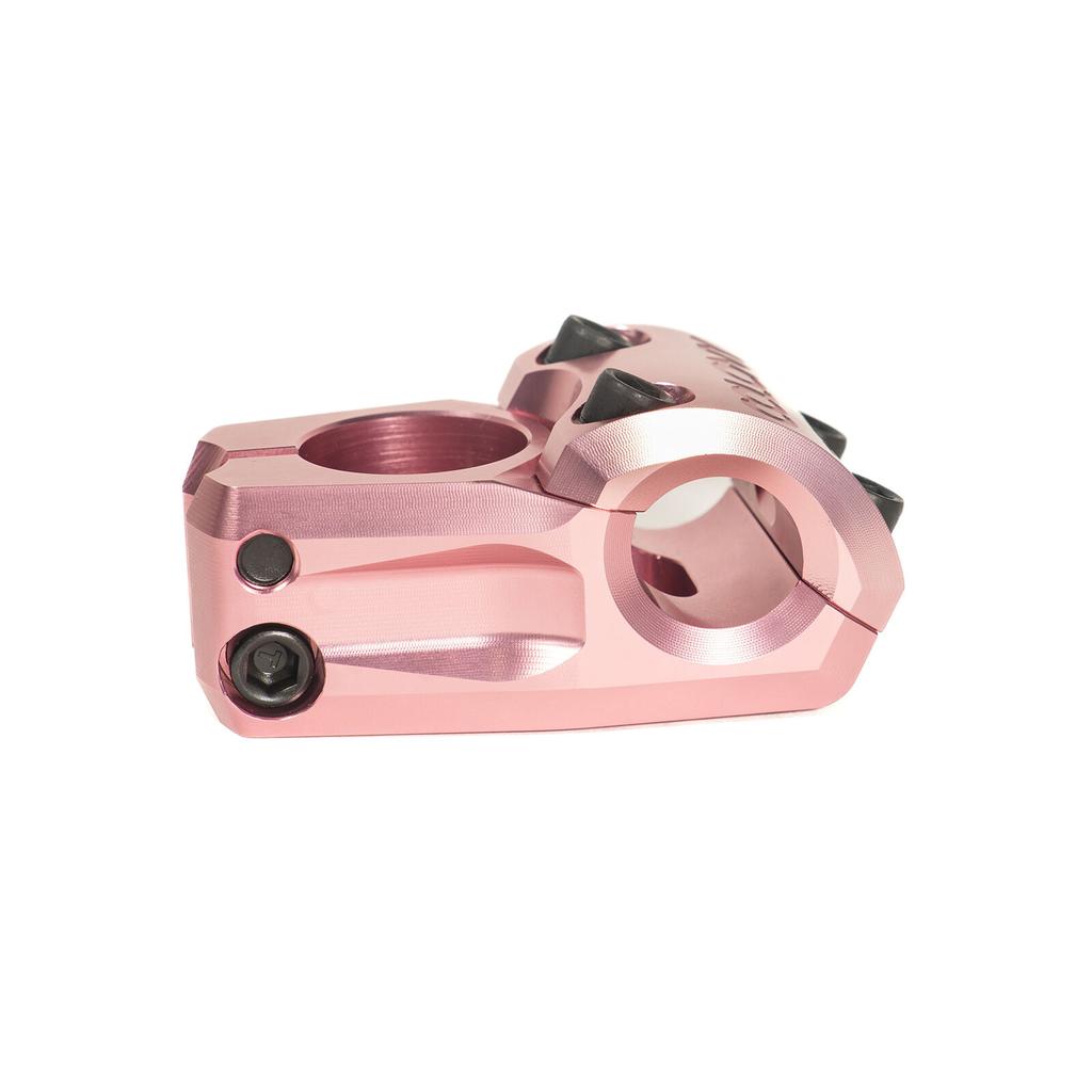 The Colony Variant 35mm Stem is a pink metal BMX stem with black bolts and three black spikes on top, designed for precision performance. This low-rise stem is shown on a white background.