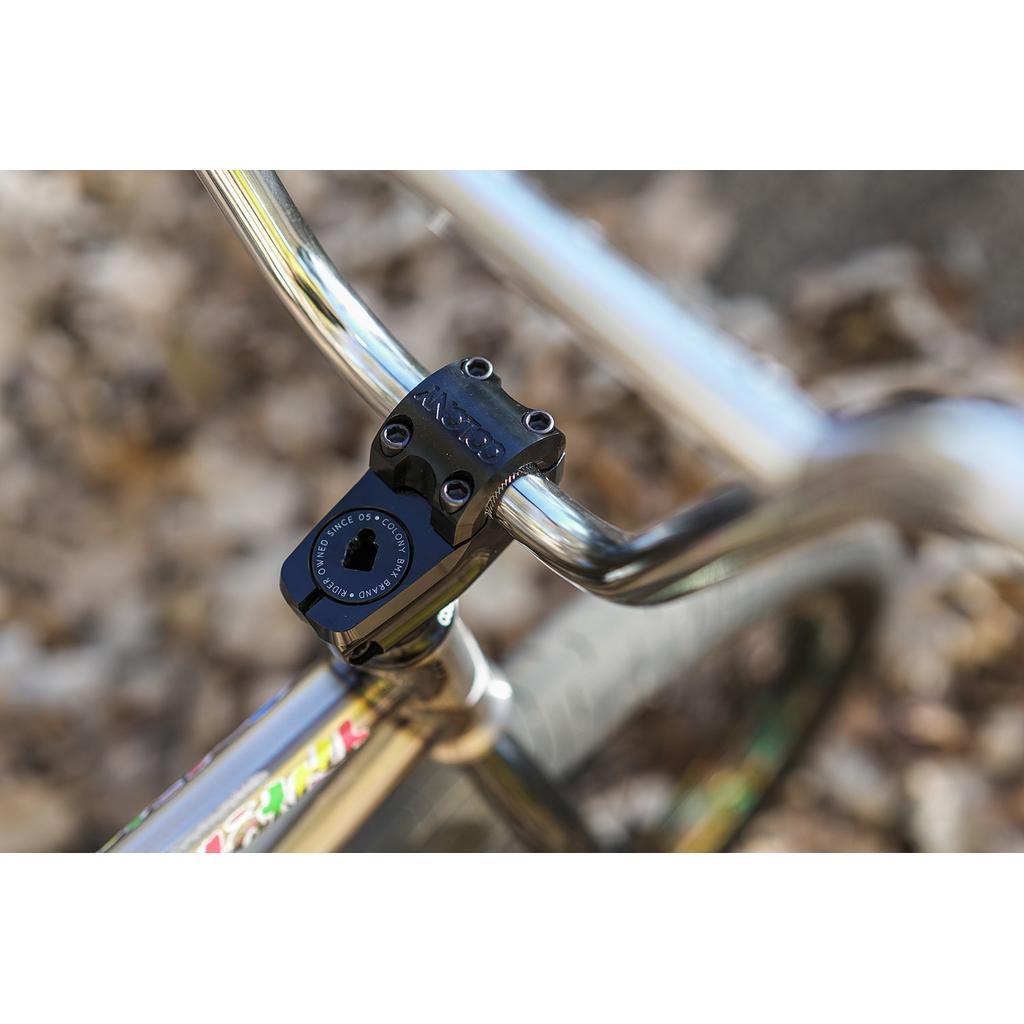 Close-up of a bicycle handlebar fitted with the Colony Squareback Stem in a top load design, set against a blurred background of fallen leaves.