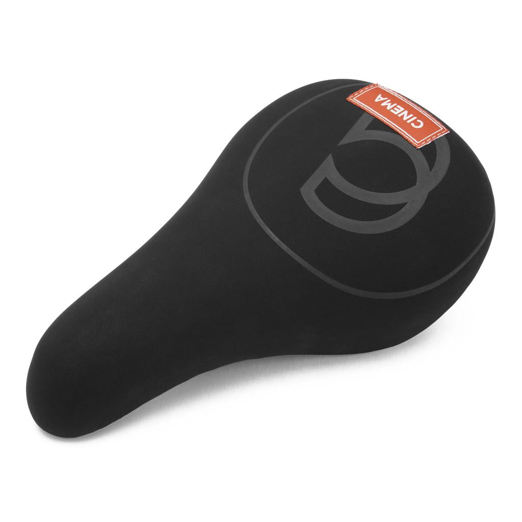 The Cinema Press Stealth Seat is a black bicycle seat with sleek design, subtle gray pattern, premium microfiber material, and a red "CINEMA" label on top.