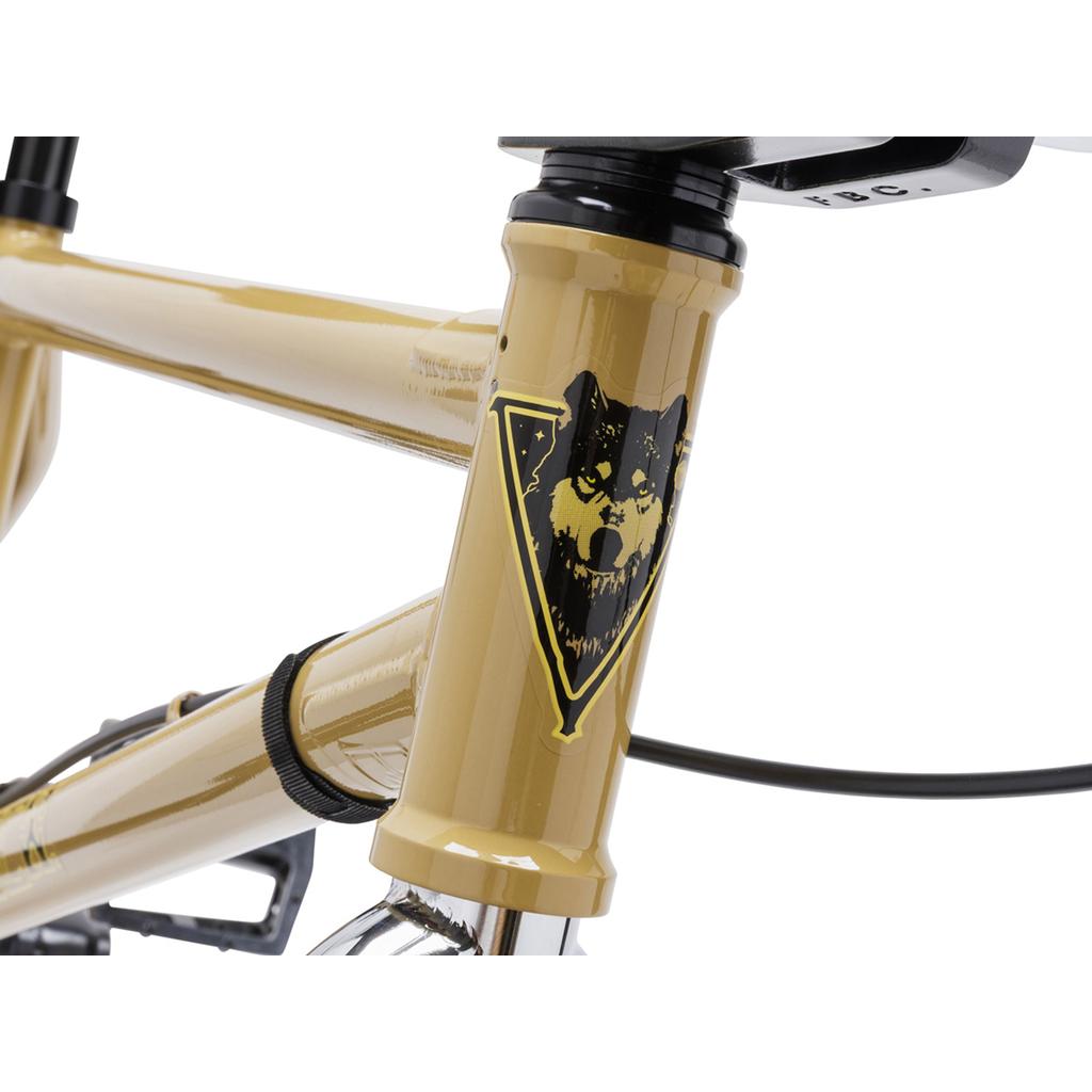 Close-up of the Fit Bike Co Nightwolf 20 Inch Bike, featuring a tan full chromoly frame with a wolf head triangle graphic on the head tube, visible cables, handlebars, and limited edition style.