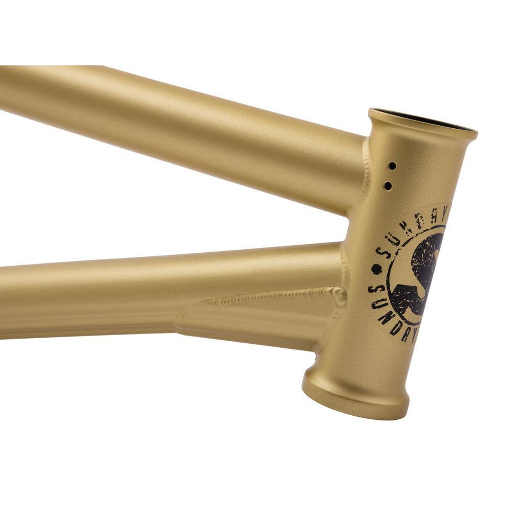 Close-up of a Sunday Wavelength Frame—matte gold chromoly BMX frame featuring a black logo and text near the head tube.