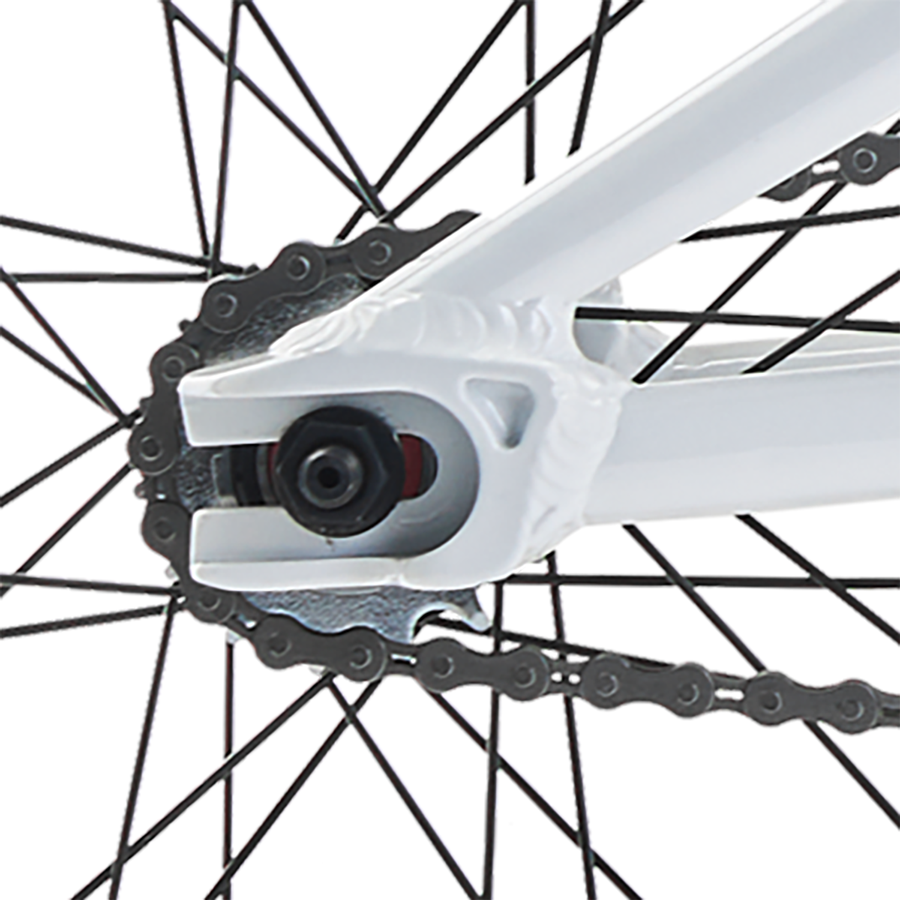 Close-up view of a white Redline Proline Expert XL Bike's rear dropout with a chain threading through the gears, focusing on the derailleur's mechanism and the wheel spokes.