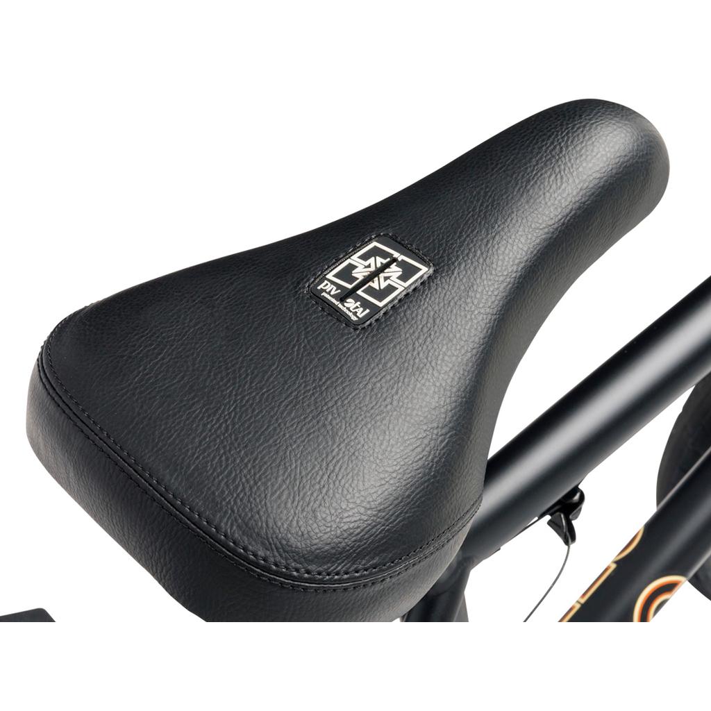 Close-up of the Fit Bike Co STR 20 Inch Bike (2026) shows its black seat with a textured surface and a square logo featuring a cross design, ideal for modern street riding.