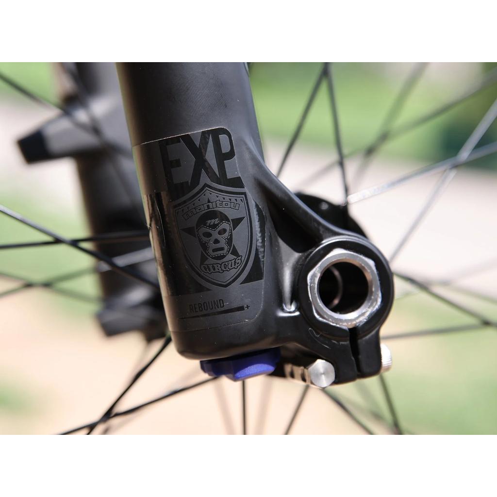 Close-up of a Fairdale Hareraiser FX 26 Inch Bike fork, featuring the "Manitou Circus" logo sticker, black spokes, and a suspension adjustment knob on the DJ frame.