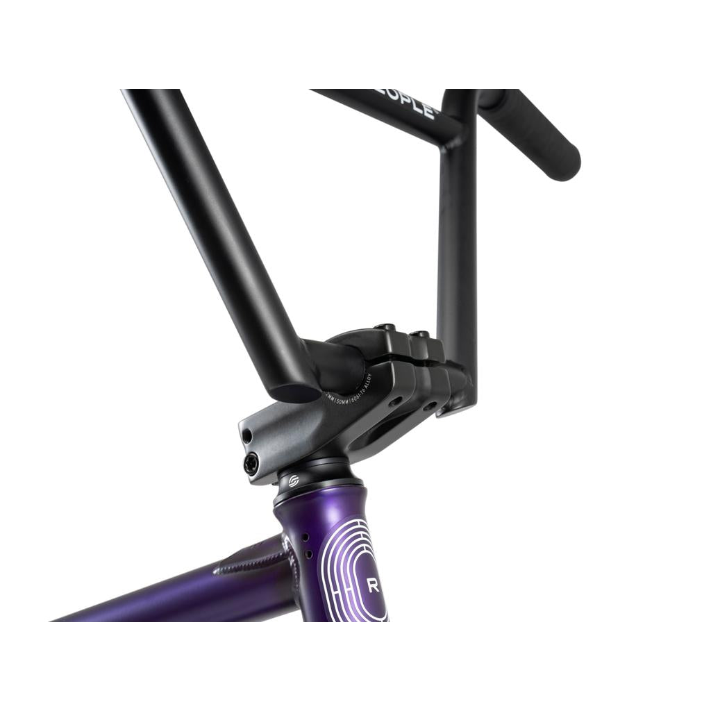 Close-up of the black handlebar and stem attached to the metallic purple frame of the Wethepeople Reason Shift 20 Inch Bike, showcasing headset details and premium BMX features.