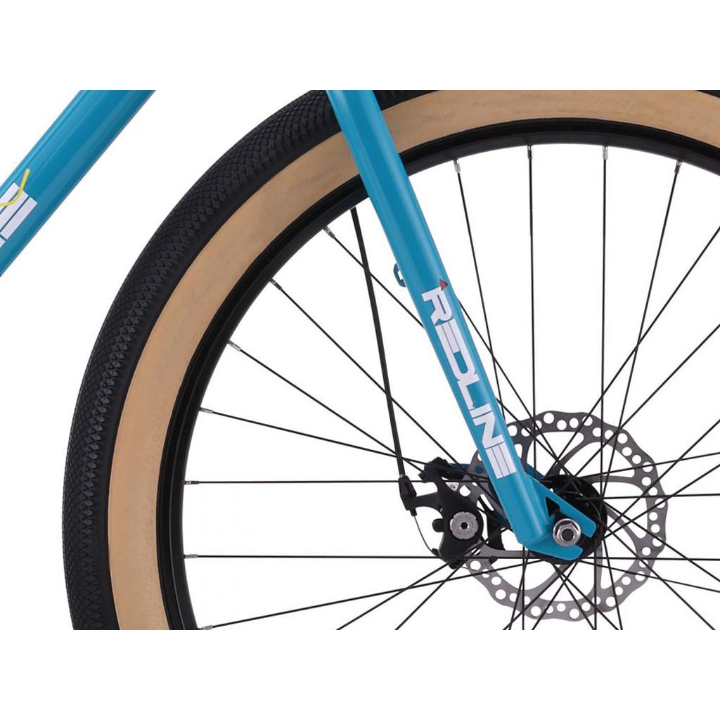 Close-up of the Redline RL 275 27.5 Inch Bike’s front wheel shows a tan wall tire, disc brake, and blue fork with "REDLINE" logo on 27.5-inch rims.