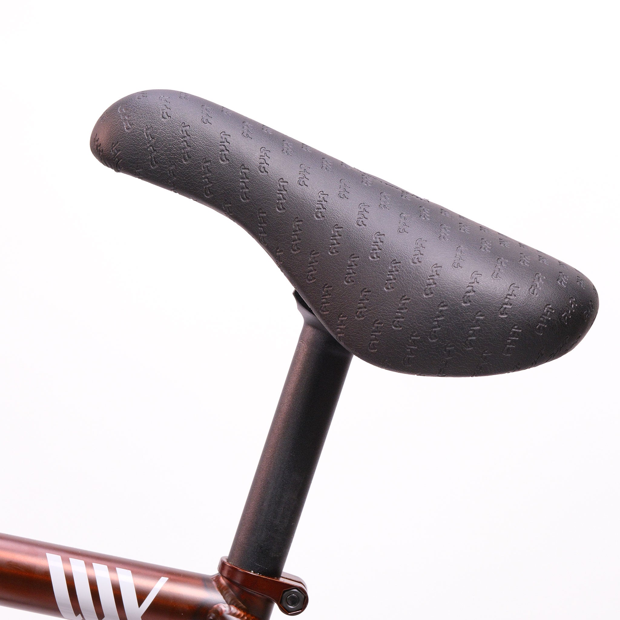 A close-up of a black bicycle seat attached to a seat post on a Cult Dak X Eclat Custom 'Pat Freyne Signature' BMX bike, set against a white background.
