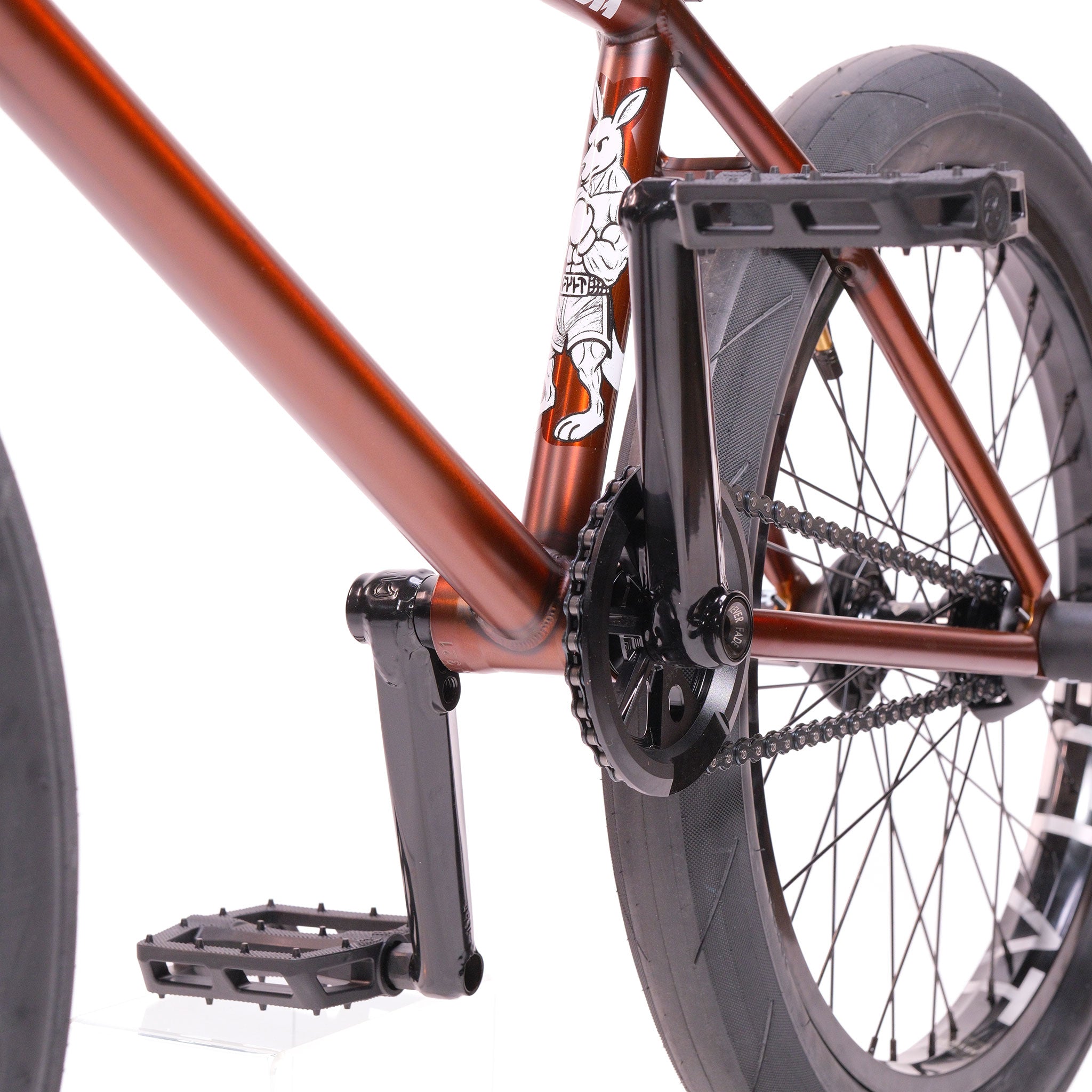 Close-up view of the rear wheel, chain, pedals, and brown Cult Dak X Eclat Custom 'Pat Freyne Signature' BMX frame with white graphic.
