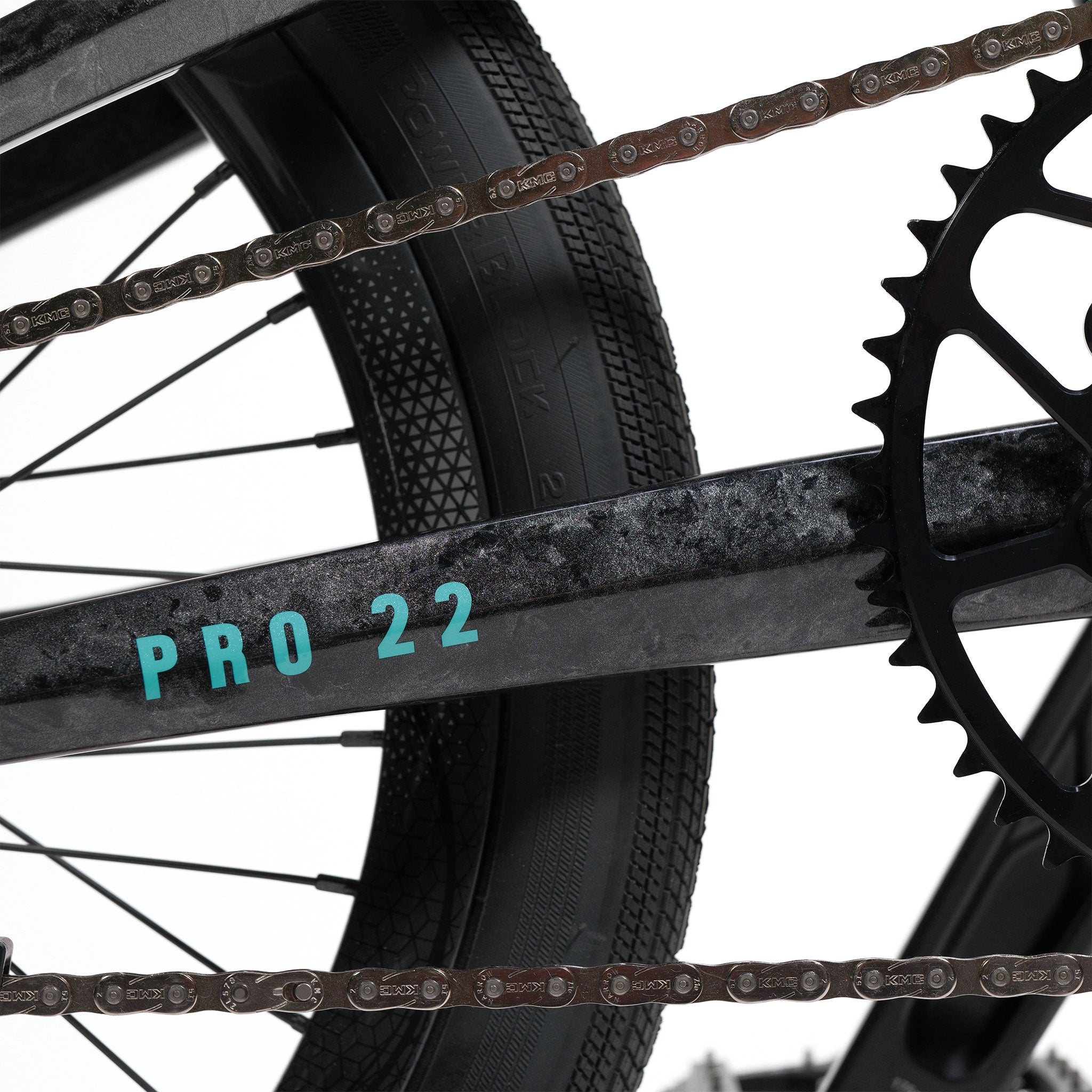 Close-up of a bicycle drivetrain, displaying the chain, gears, a sleek black frame labeled "PRO 22," and part of the rear tire—highlighting design elements inspired by the Meybo HSX Carbon Pro XXL Race Bike.