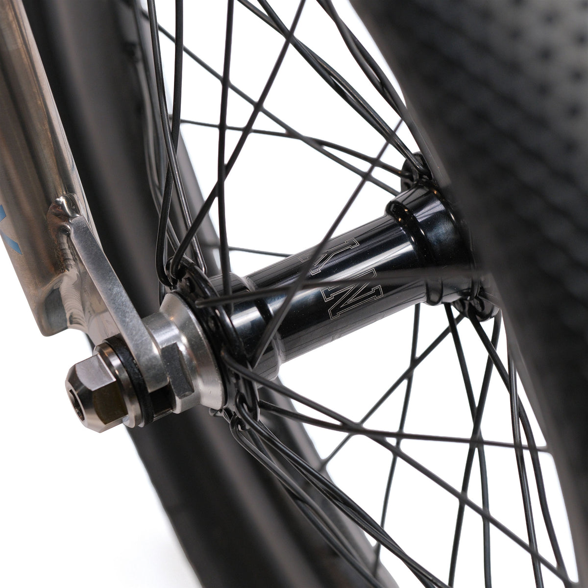 Close-up of the ION BMX Ti16 Custom Titanium 16 Inch Bike’s lightweight wheel hub, featuring black spokes, axle, and tire against a white background.