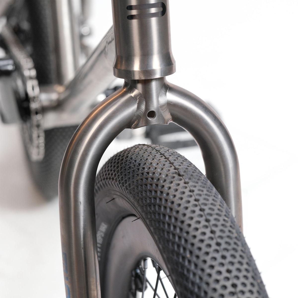 Close-up of the ION BMX Ti16 Custom Titanium 16 Inch Bike’s front tire and fork, highlighting its clean, minimalist design with a lightweight titanium frame and knobby tread, set against a white background.