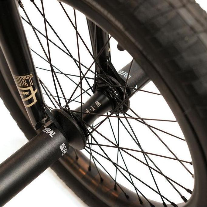 Close-up of the Federal Boyd x ION Custom 18 Inch Bike's BMX rear wheel, highlighting black spokes, treaded tire, and a metal peg on the axle—ideal features for any freestyle rider.