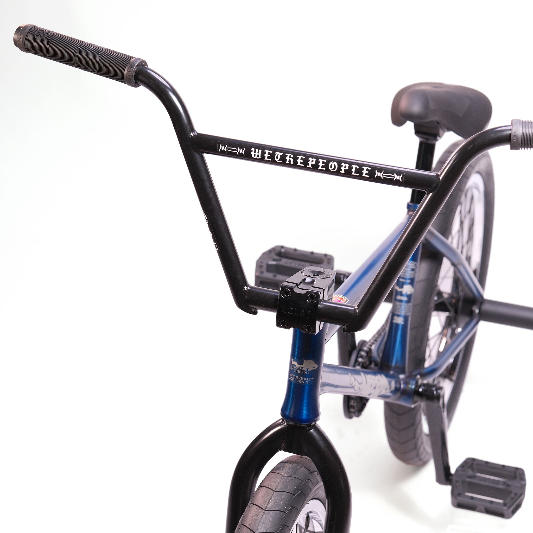 Close-up of a Wethepeople Tomorrow X TA Custom build BMX bike with a blue frame, black "WETHEPEOPLE" handlebars, Eclat Storm TA Forks, black pedals, and a black seat shown against a white background.