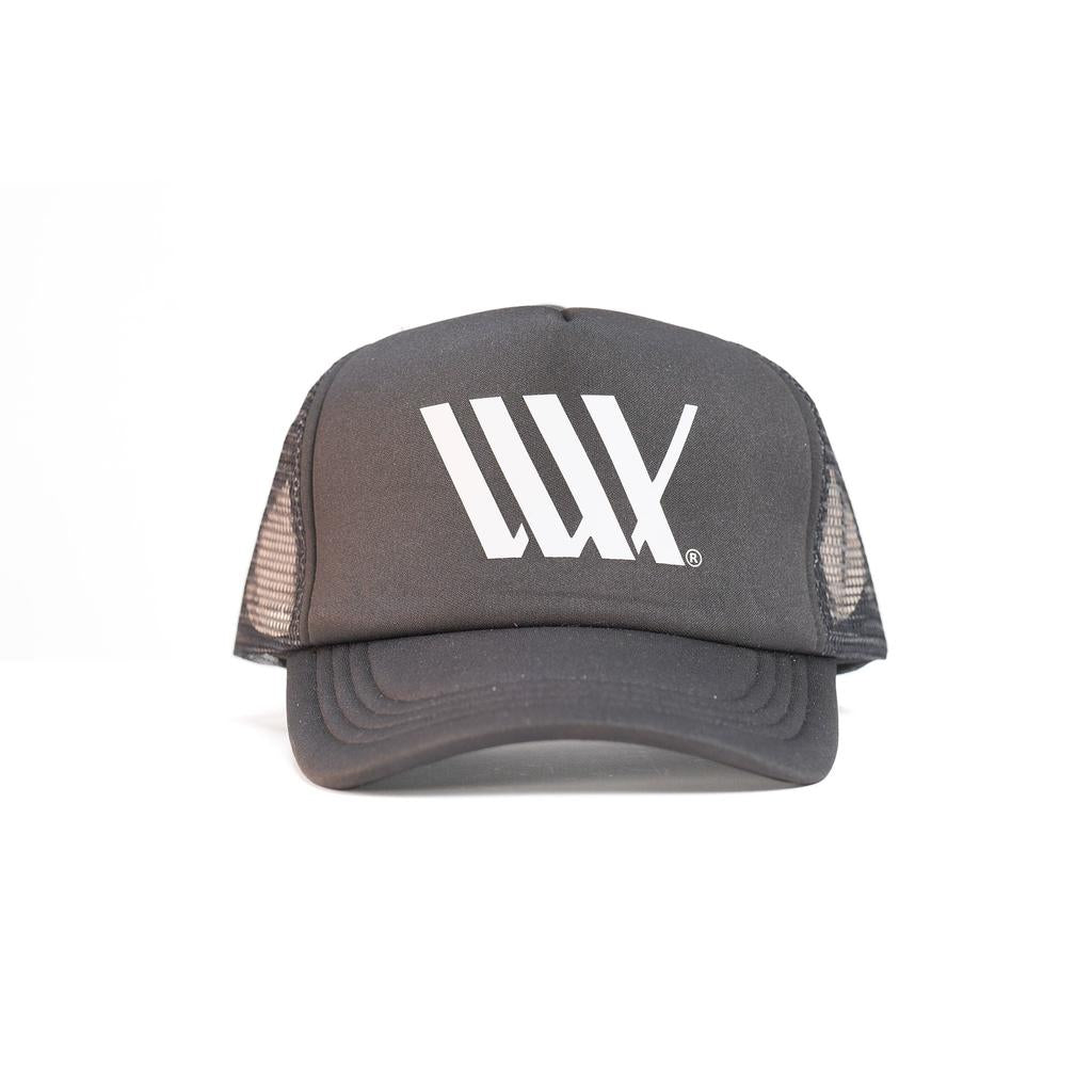 The LUXBMX Flag Trucker Cap features a black design with mesh sides made from recycled polyester and a white "LUX" logo on the front, photographed on a plain white background. Ideal for adding Brisbane style and comfort to any outfit.